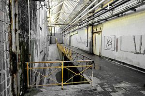 Usine Aabe de Tilburg en noir et blanc avec une clôture jaune.