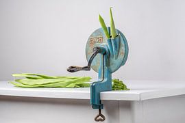 Still life / Antique string bean mill with string beans on a white wooden table by Photography art by Sacha