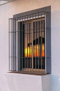 Sonnenuntergang spiegeln sich in einem Fenster einer weißen Fassade. Rota, Costa de la Lutz, Cádiz, Andalusien, Spanien
