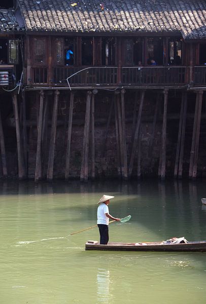 Un homme navigue dans un village chinois traditionnel. par Floyd Angenent