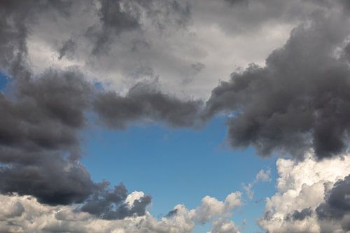 Clouds in all colors: black, gray, white. Blue sky in the background.