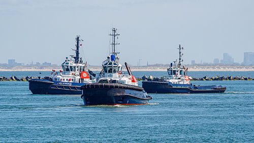 Drei Hafenschlepper warten auf einen Supertanker.