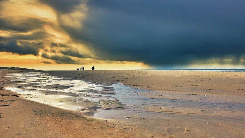 Donkere wolken met wandelaars op het strand van eric van der eijk