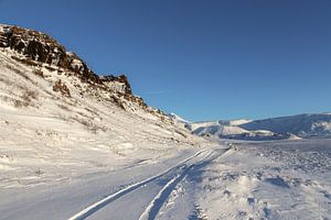 Traces de roues sur une route enneigée en Islande sur Mickéle Godderis