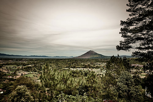 A vast rural landscape beneath Mount Sinabung