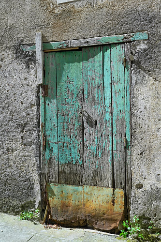 Vieille porte en bois dont la peinture s'écaille et dont la surface est altérée par les intempéries