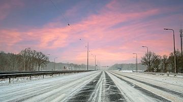 Conduite d'une voiture dans une tempête de neige sur l'autoroute A1 près d'Amsterdam, aux Pays-Bas, en hiver, au coucher du soleil. sur Eye on You
