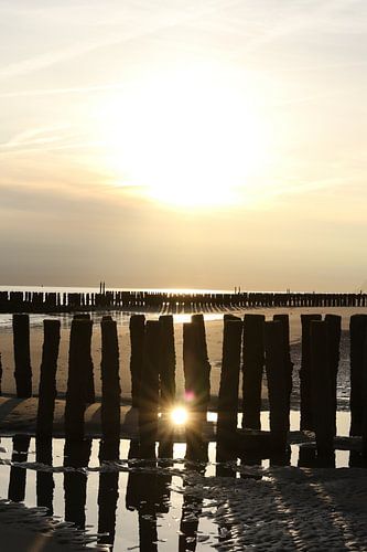 golfbrekers met ondergaande zon op het strand in zeeland