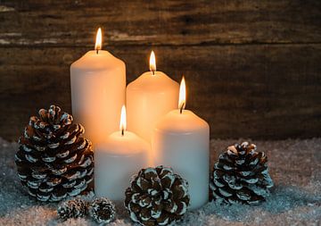 Vier witte brandende kaarsen met kerstversiering en houten achtergrond van Alex Winter