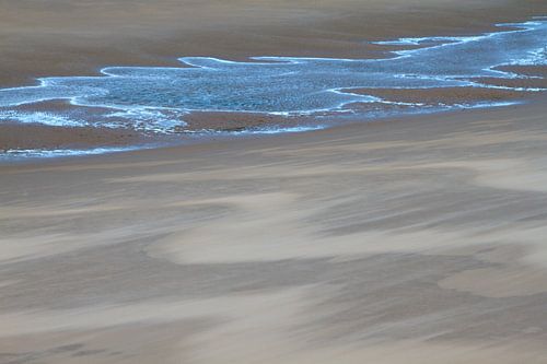 Windvegen in het zand en blauw reflecterend water