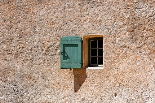Raam in oud Frans landelijk huis. Groene luiken en terracotta muur