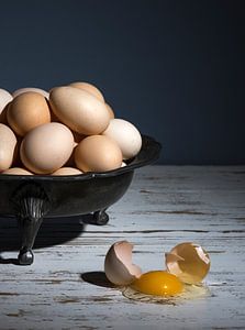 Nature morte avec un plat en étain avec une pile d'œufs et un œuf cassé sur une table blanche à fond
