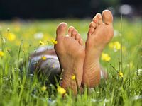 Soles of bare feet in flowerfield, close up