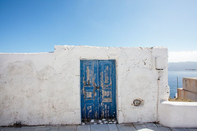 Weiße Wand und blaue Tür vor dem Hintergrund des blauen Meeres auf Santorini, Griechenland von WorldWidePhotoWeb