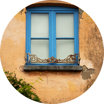 Mediterrane muur met blauw raamkozijn.