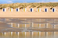 Strandhuisjes weerspiegeld in het water van de zee