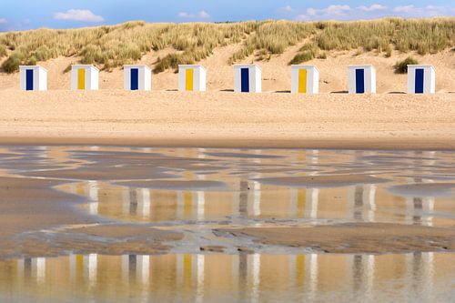 Strandhuisjes weerspiegeld in het water van de zee