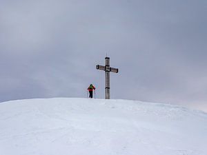 Bergsteiger auf einem Gipfelkreuz in den Alpen von Animaflora PicsStock