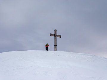 Bergbeklimmers op een bergtopkruis in de Alpen