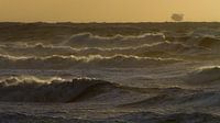 Surf during storm with sunset and oil rig