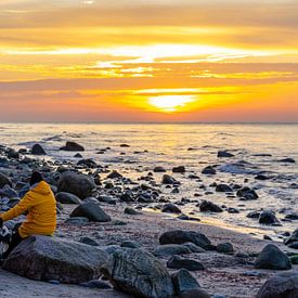 Jong stel in gele regenjassen op een kiezelstrand met rotsen bij zonsondergang op het Oostzee-eiland Rügen van Animaflora PicsStock
