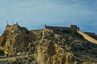 Le Castillo de Santa Bárbara à Alicante sur une montagne rocheuse sous un ciel bleu clair.