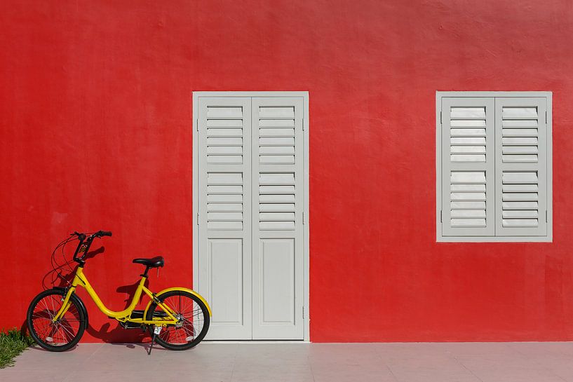 Mur rouge avec vélo d'enfant jaune par Jan van Dasler