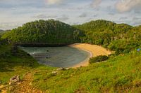 Plage de sable du lagon Kasap avec des collines verdoyantes.