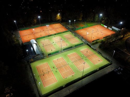 Dronefoto van helder verlichte tennisbanen in de avonduren