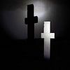 White cross with shadow in the darkness by Frank Herrmann