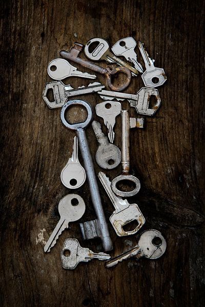 Verschiedene alte Schlüssel in Form eines Schlüssellochs auf einem dunklen, rustikalen Holzbrett, ve von Maren Winter