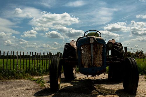 Blauwe oude roestige tractor in landelijke omgeving