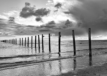 Schwarze und weiße Strandmasten im Meer, bedrohlicher Himmel von Marjolein van Middelkoop