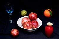 Apfelsine, Granatapfel und Cherimoya mit blauem Weinglas und rot