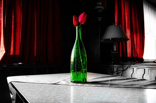 Stillleben im Verfall – Grüne Flasche mit roten Blüten im verlassenen Raum