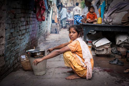 Indian girl washing dishes on the slum streets of Varanasi in India. Wout Kok One2expose