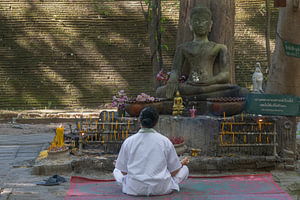 Meditation vor einer Buddhastatue in Thailand