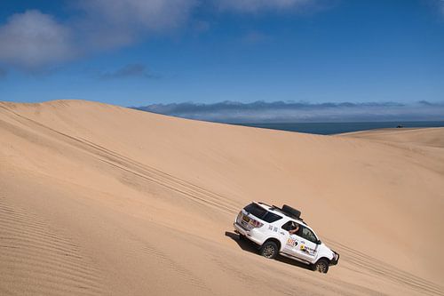 Een terreinwagen die een zandduin afrijdt
