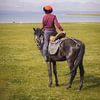 Un jeune cavalier kirghize regarde le lac Soň-Köl sur Mark Sluijmers