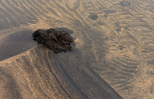 Vulkanische rots en zand patronen in het water