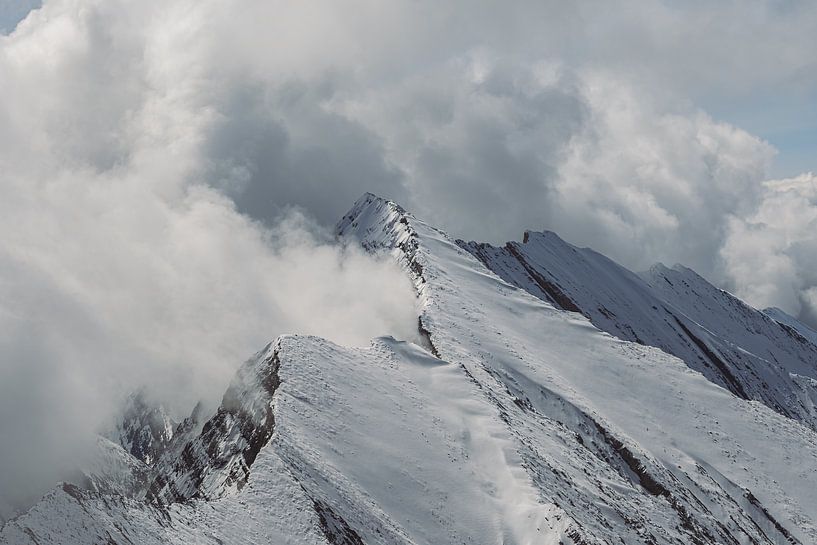 Verschneiter Berggipfel zwischen den Wolken von Eline Huizenga
