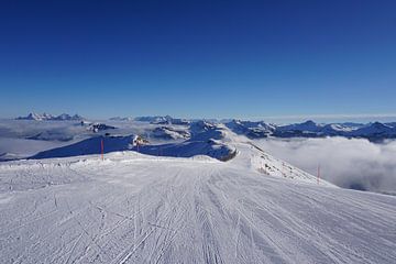 Skipiste in Kitzbühel, Tirol (Oostenrijk) omringd door bergtoppen en bewolking van Kelly Alblas