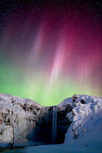 Red and green glowing aurora over Skogafoss by Sascha Kilmer