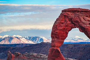 Die schneebedeckten Gipfel der Rocky Mountains hinter dem Delicate Arch