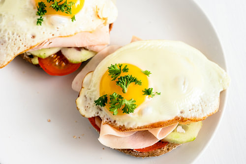 Spiegelei auf Vollkornbrötchen mit Tomate, Gurke und gekochtem Schinken, gesundes, herzhaftes Frühst