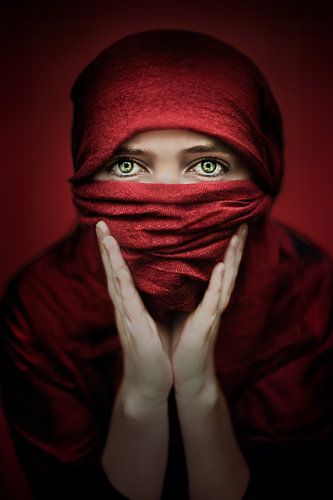 Indringende Foto van Vrouw in Rode Sluier - Krachtige Blik met Groene Ogen