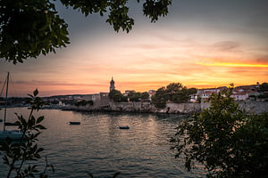Blick durch Bäume auf die Altstadt von Krk, Kroatien