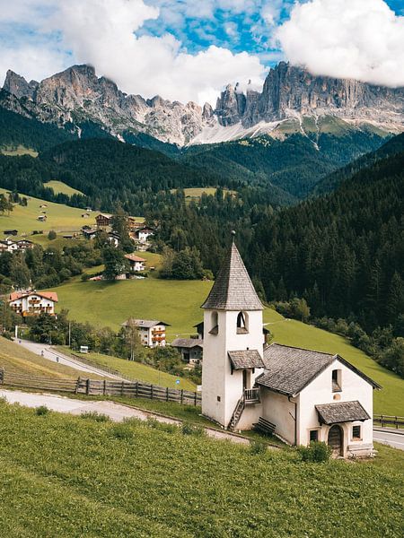 Kerk in de Italiaanse dolomieten met de ruige bergen in de wolken op de achtergrond. van Michiel Dros