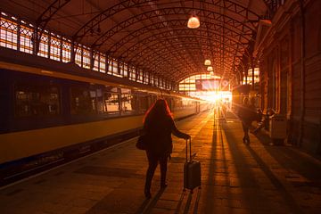 Silhouetten van reizigers op treinstation tijdens zonsondergang