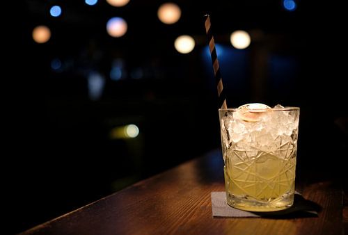 Leckerer Cocktail auf Eis mit Lichtern im Hintergrund von Lensw0rld